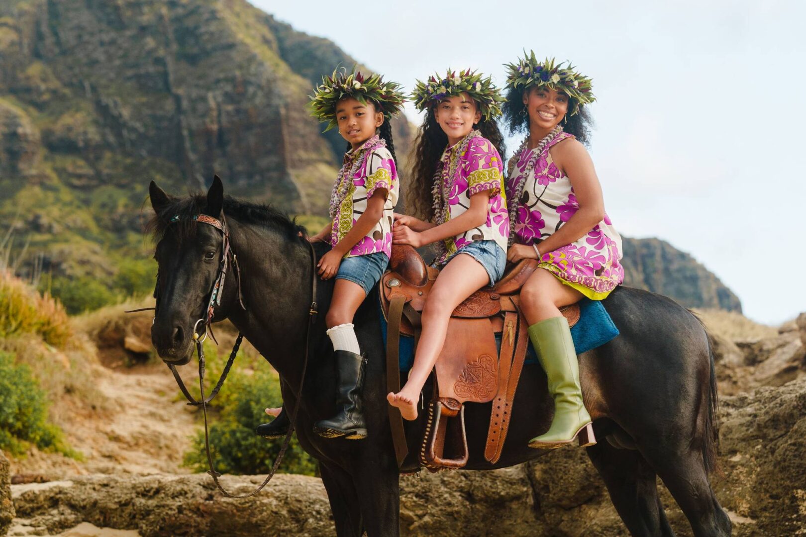 Three girls in hawaiian shirts on a horse.